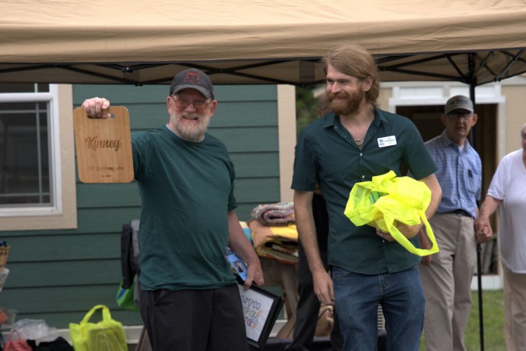 An image of two men in the foreground of a house built by Habitat for Humanity of Missoula. 